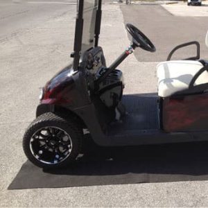 Golf cart parked on a garage parking mat for protection and organization.